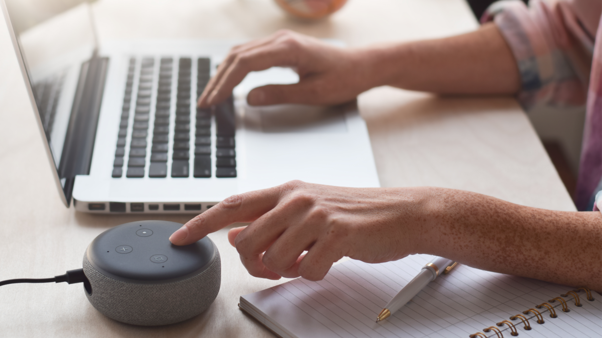 Pessoa utiliza assistente virtual por comando de voz ao lado de notebook, destacando tecnologia assistiva e acessibilidade digital.
