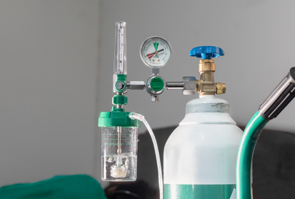 Cilindro de oxigênio medicinal com regulador de pressão, manômetro, fluxômetro graduado em L/min e frasco umidificador. Equipamento utilizado para controle seguro do fluxo de oxigênio em oxigenoterapia hospitalar e domiciliar.