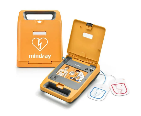 Desfibrilador externo automático (DEA) da marca Mindray com tampa aberta, tela ilustrativa de instruções e eletrodos adesivos. Equipamento utilizado para atendimento de parada cardiorrespiratória em emergências.