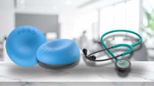 Dispositivo médico digital portátil azul ao lado de estetoscópio tradicional, comparando tecnologia de ausculta digital e método convencional.