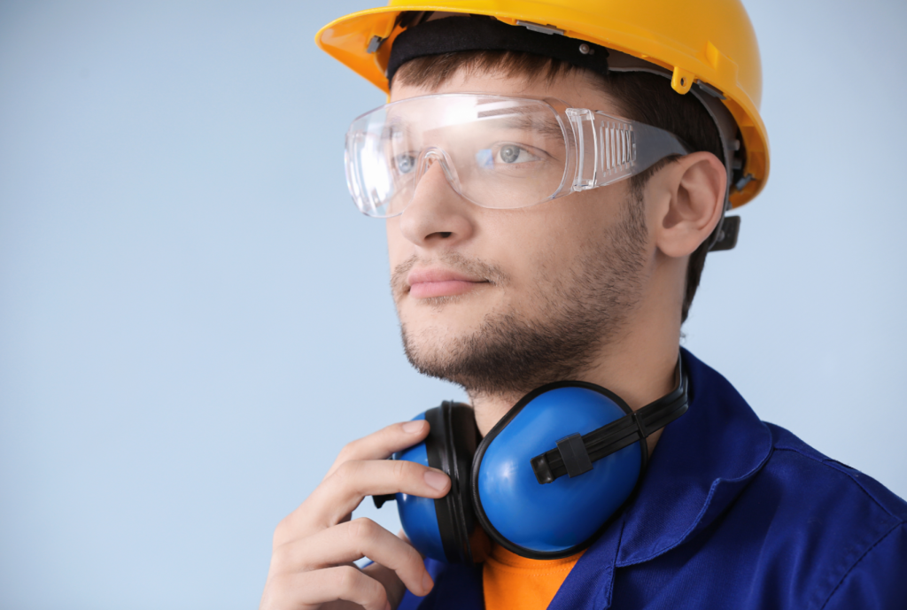 Trabalhador utilizando equipamentos de proteção individual (EPI), incluindo capacete de segurança, óculos de proteção e protetor auricular. Itens essenciais para segurança no trabalho em ambientes industriais e de construção.