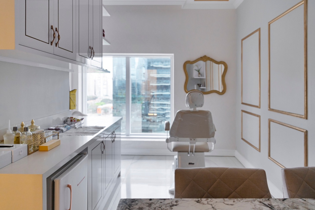 Sala de atendimento estético ou clínico com cadeira reclinável, bancada com produtos e equipamentos organizados. O ambiente é moderno, bem iluminado e preparado para procedimentos de cuidados pessoais ou atendimentos de saúde.