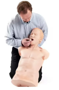 Instrutor demonstrando técnica de ressuscitação cardiopulmonar (RCP) em manequim de treinamento. A prática simula procedimentos de emergência para reanimação em casos de parada cardiorrespiratória durante cursos de primeiros socorros.