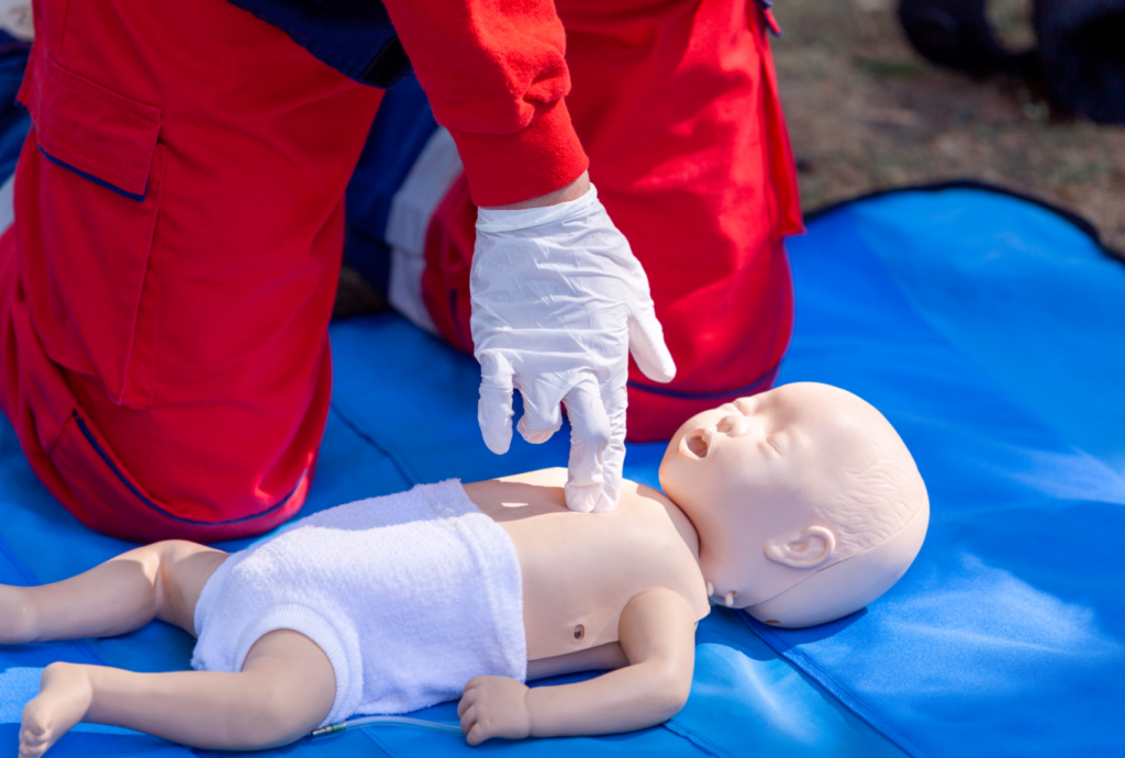 Imagem demonstrando compressão torácica em RCP neonatal realizada em manequim de bebê. Técnica essencial no suporte básico de vida para atendimento de parada cardiorrespiratória em recém-nascidos e lactentes.