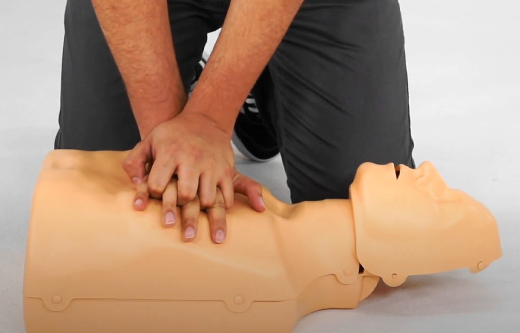 Imagem mostra compressões torácicas na ressuscitação cardiopulmonar (RCP) em adulto, realizadas em manequim de treinamento. Técnica essencial de primeiros socorros para parada cardiorrespiratória e suporte básico de vida.